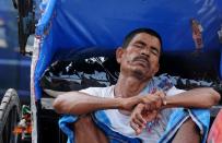 An Indian rickshaw-puller sleeps at the roadside in Kolkata, on May 27, 2015