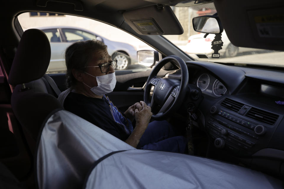 Marta Rosales waits in line for food at a distribution center Thursday, July 23, 2020, in Brawley, Calif. Rosales, who suffers from various health issues, rarely leaves her home during the coronavirus outbreak. She says the food she receives at the distribution center has been a savior. (AP Photo/Gregory Bull)