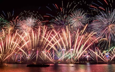 Fireworks explode over Victoria Harbour during New Year celebrations in Hong Kong - Credit: AFP