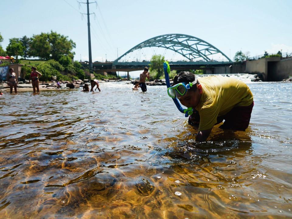 People cool off in the water at the confluence of the South Platte River and Cherry Creek in Denver, Monday, June 14, 2021.