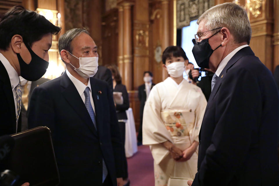 ADDS RESTRICTION: ONE TIME USE ONLY, EDITORIAL USE ONLY - IOC President Thomas Bach, right, meets with Japanese Prime Minister Yoshihide Suga, second from left, during a welcome party for Bach and IOC officials at Akasaka Palace, Japanese state guest house, in Tokyo, Japan, Sunday, July 18, 2021.(Courtesy of Tokyo 2020 via AP)