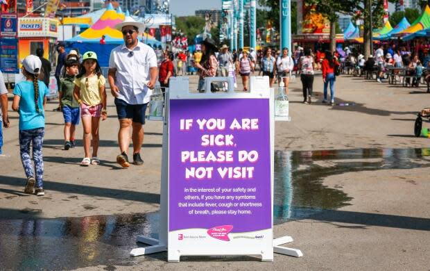 A COVID-19 precaution sign is shown at the Calgary Stampede on July 9. Organizers said they were confident that new safety measures adopted by the festival would essentially see the Stampede function like a blueprint for other mass gatherings scheduled this year across Canada. (Jeff McIntosh/The Canadian Press - image credit)