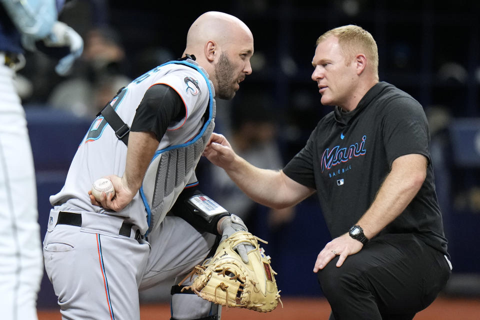 The Miami Marlins trainer, right, checks on catcher Jacob Stallings after he was hit with a foul ball by Tampa Bay Rays' Josh Lowe during the second inning of a baseball game Tuesday, July 25, 2023, in St. Petersburg, Fla. Stallings stayed in the game. (AP Photo/Chris O'Meara)