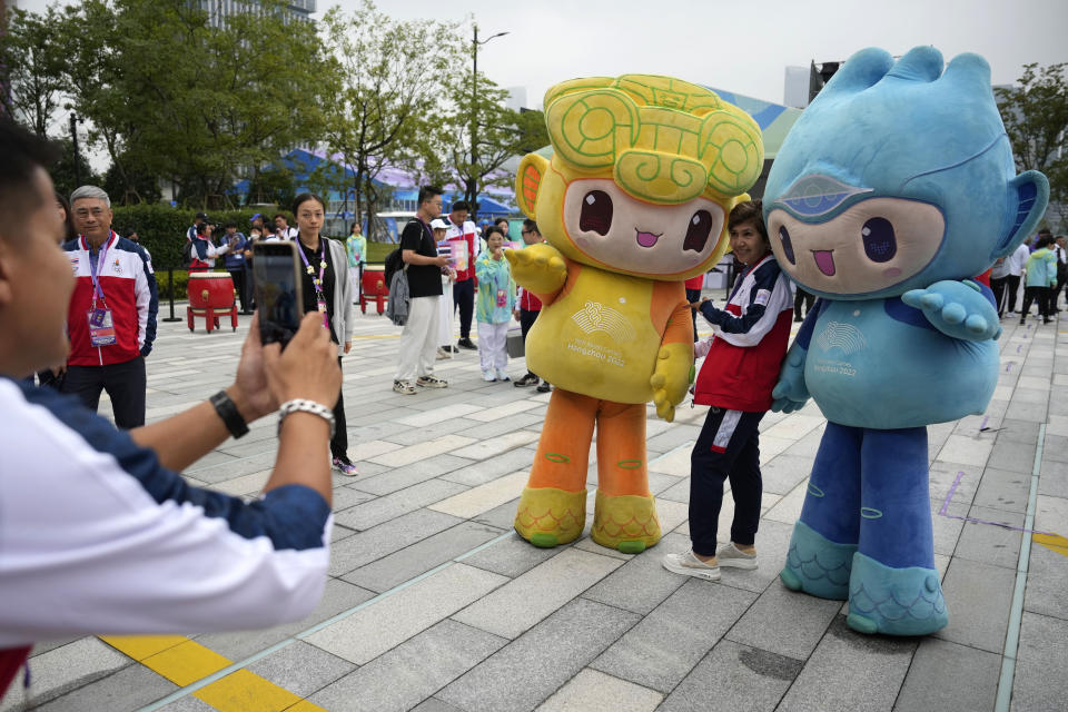 A member of Team Thailand has her photo taken with the 19th Asian Games mascots Chenchen and Congcong, during a team welcoming ceremony at the 19th Asian Games in Hangzhou, China, Friday, Sept. 22, 2023. (AP Photo/Aaron Favila)