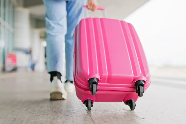 <p>Getty</p> Stock image of person walking in airport with pink suitcase
