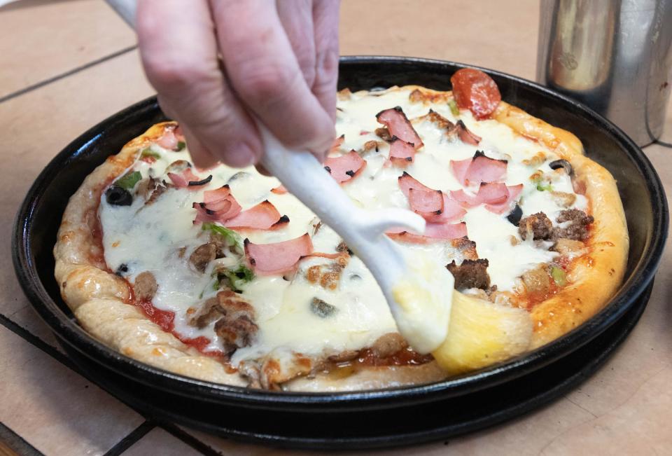 Owner Carl Hixson brushes garlic butter on the crust of a House Special pizza at Georgio's Pizza on East Cervantes Street in Pensacola on Wednesday, Jan. 31, 2024.