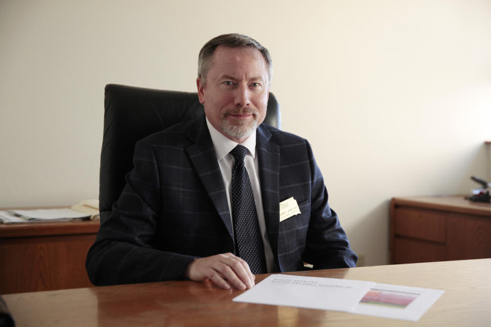 Ben Jones, who oversees the the South Dakota Historical Society, sits for a portrait with a copy of South Dakota's proposed social studies standards in Sioux Falls, S.D., on Sept. 1, 2022. He worked on the South Dakota Social Studies Standards Commission, which was led by a former Hillsdale College professor. (AP Photo/Stephen Groves)