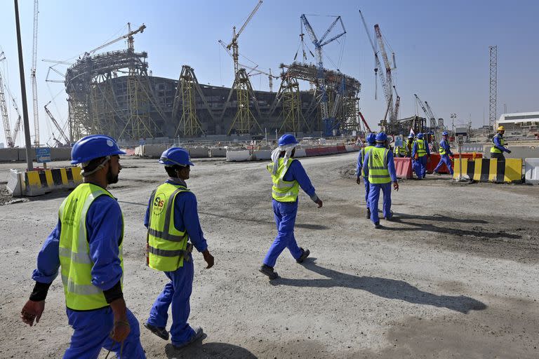 (FILES) This file photo taken on December 20, 2019, shows construction workers at Qatar's Lusail Stadium,  one of the Qatar's 2022 World Cup stadiums, around 20 kilometres north of the capital Doha. - Fifty migrant workers died in Qatar last year and over 500 were seriously injured, the UN's International Labour Organization said on November 19, as the Gulf nation readies for the 2022 World Cup. (Photo by GIUSEPPE CACACE / AFP)