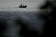 In this photo taken Friday, May 22, 2020, people boat on Shawnee Mission Lake at dusk in Lenexa, Kan. As warm weather approaches and many public pools remain closed to prevent the spread of COVID-19, there has been a surge of people using backyard pools as well at taking to water activities on lakes and rivers to get out and cool off. (AP Photo/Charlie Riedel)