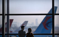 A traveler wearing a face mask to protect against the coronavirus stands at a boarding gate at the Shanghai Hongqiao International Airport in Shanghai, Friday, Nov. 6, 2020. With the COVID-19 outbreak largely under control within its borders, air travel in China has mostly returned to pre-pandemic levels. (AP Photo/Mark Schiefelbein)