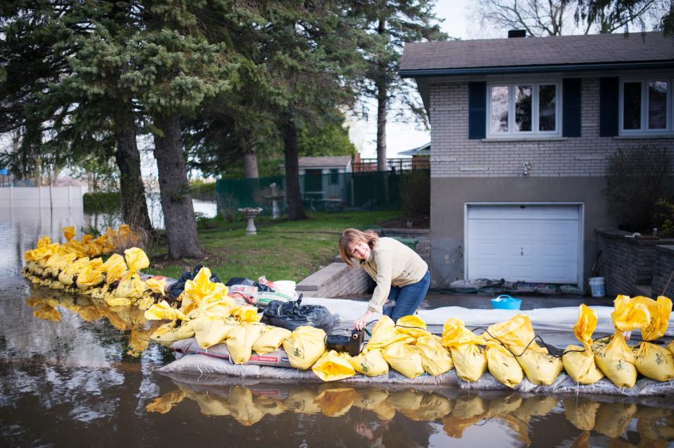 Johanne Aubin, resident of the Montreal borough of Pierrefonds, uses a pool pump to protect her home from flood waters on May 8, 2017. With heavy rains persisting and waters still rising over much of waterlogged eastern Canada, the nation's military tripled the number of troops urgently working to evacuate thousands of residents. Montreal Mayor Denis Coderre declared a state of emergency for his city, allowing authorities to order mandatory evacuations from threatened areas. / AFP PHOTO / Catherine Legault        (Photo credit should read CATHERINE LEGAULT/AFP/Getty Images)