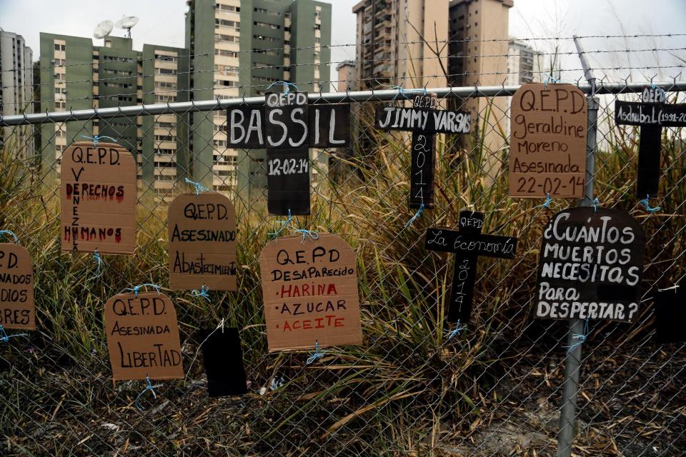 Cartones con forma de lápidas y cruces cuelgan de una reja con los nombres de las personas muertas en las protestas de las últimas semanas en Caracas, Venezuela, el miércoles 5 de marzo de 2014. El este de la capital venezolana amaneció el miércoles en medio de tensiones luego de que decenas de manifestantes bloquearon algunas vías en protesta contra el gobierno, mientras en otro extremo de la ciudad centenares de personas se preparaban para conmemorar el primer aniversario de la muerte de Chávez. (AP foto/Fernando Llano)