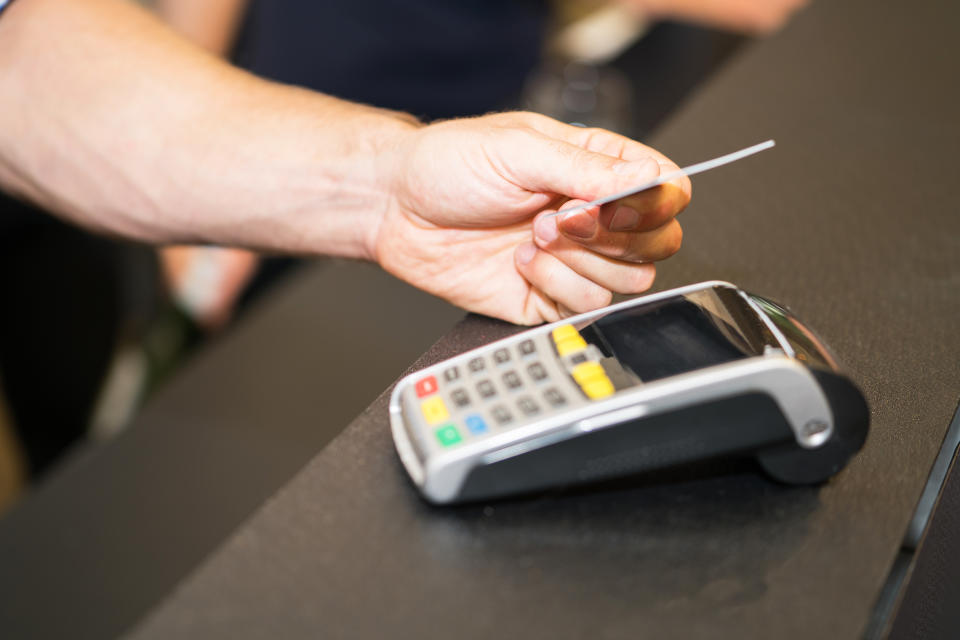 Focus on hand making credit card payment closeup with male hand holding card above reader.