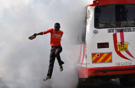 A supporter of Kenyan opposition leader Raila Odinga of the National Super Alliance (NASA) coalition jumps from a bus after riot police fired teargas canisters to disperse them after his swearing-in ceremony in Nairobi, Kenya January 30, 2018. REUTERS/Isaac Biosse