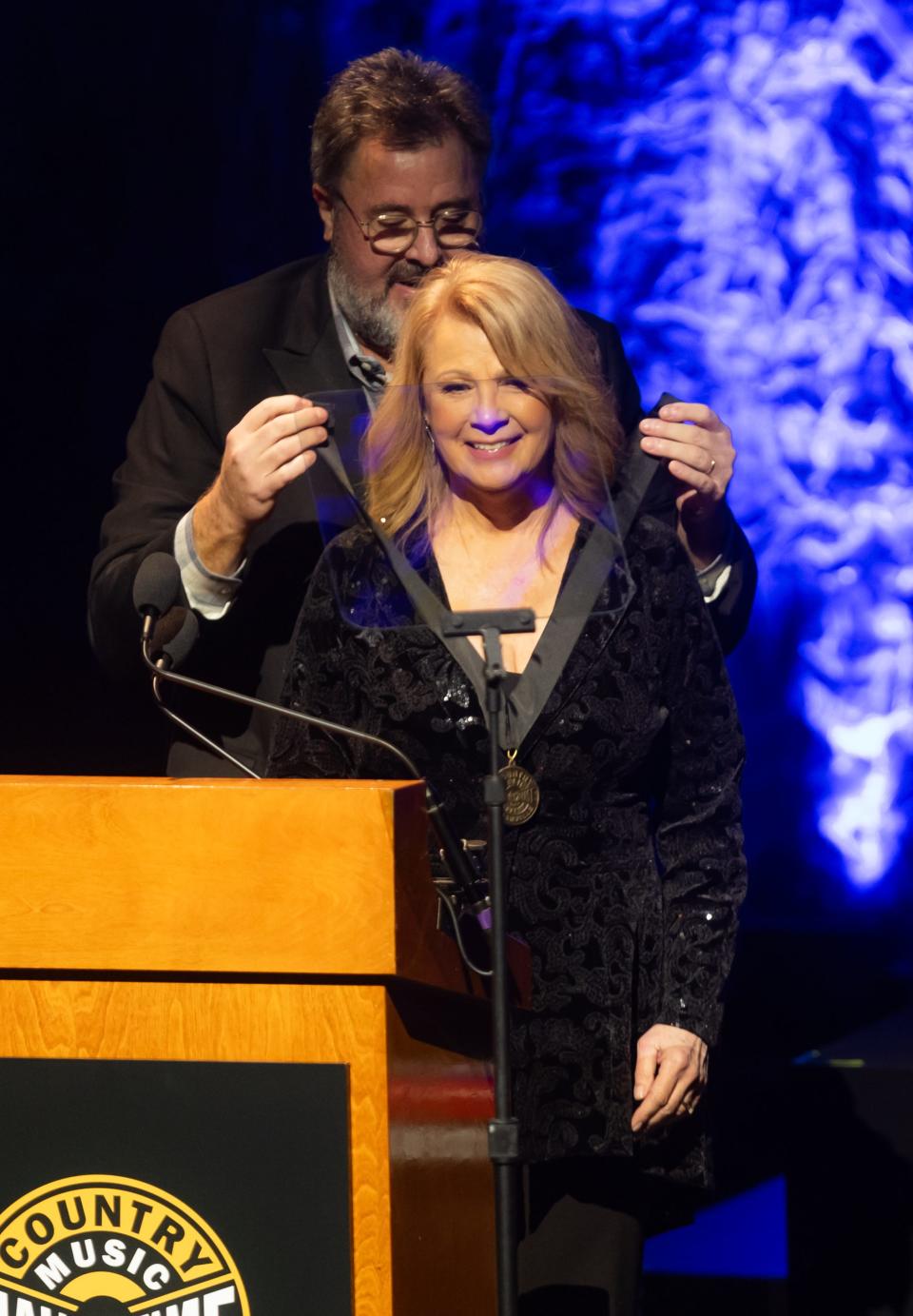 Vince Gill puts the hall of fame medallion around the neck of inductee Patty Loveless during the 2023 Country Music Hall of Fame induction ceremony Sunday, October 22, 2023.