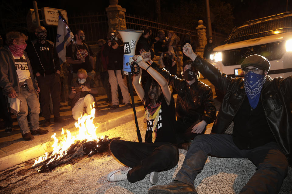 Israeli protesters chant slogans and block a road during a demonstration against Israeli Prime Minister Benjamin Netanyahu near his official residence in Jerusalem during the third nationwide coronavirus lockdown, Saturday, Jan. 2, 2021. (AP Photo/Ariel Schalit)