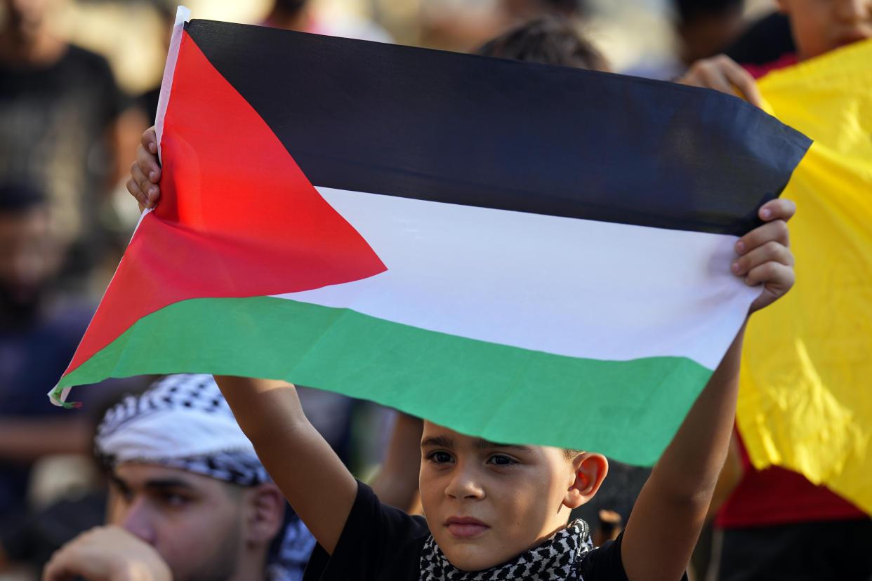 A boy holds up a Palestinian flags during a rally in solidarity with the Palestinian people in Gaza, at Bourj al-Barajneh Palestinian refugee camp, in Beirut, Lebanon, Wednesday, Oct. 11, 2023. (Bilal Hussein/AP)