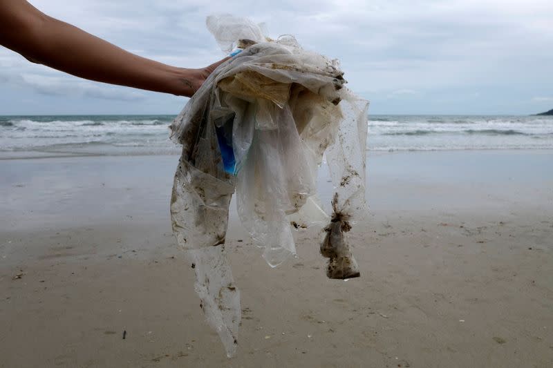 FILE PHOTO: Tourist collects plastic items washed up by the sea at the Ao Phrao Beach, on the island of Ko Samet