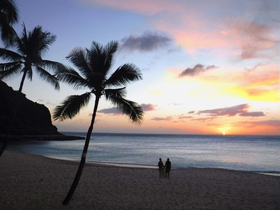 A couple on the beach at sunset in Oahu.