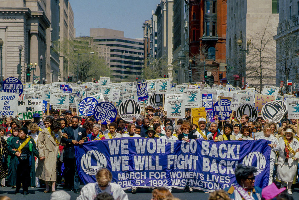 Demonstrators hold a banner reading "we won't go back, we will fight back"