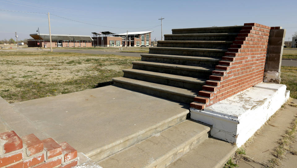 In this photo taken April, 18, 2014, a new community center rises in the distance beyond stairs leading to where a house once stood in Greensburg, Kan. Seven years after an EF-5 tornado destroyed most of the community of 1,500, Greensburg's population is around 850 residents. (AP Photo/Charlie Riedel)