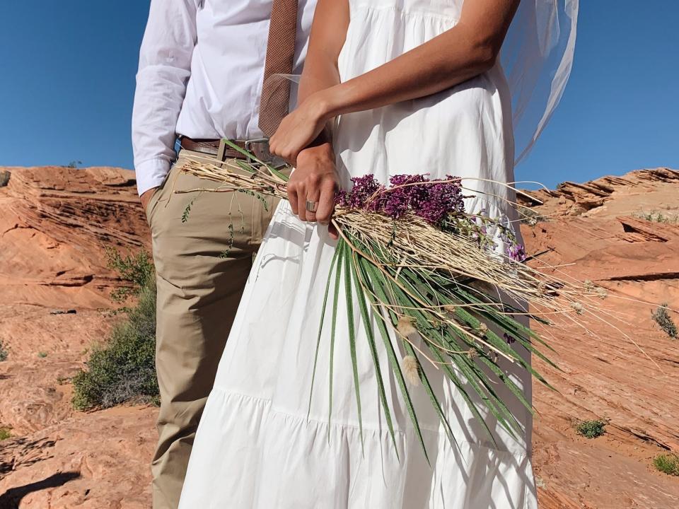 A woman holding a bouquet of flowers with her husband standing behind her.