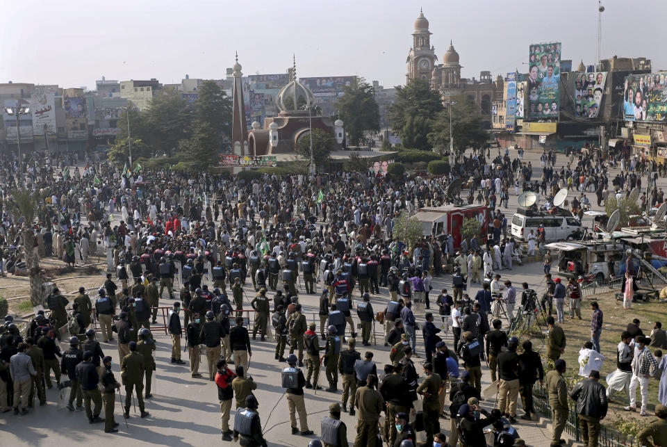Pakistani police officers stand guard while supporters of the Pakistan Democratic Movement, an alliance of opposition parties, gather at a main intersection before an anti-government rally, in Multan, Pakistan, Monday, Nov. 30, 2020. Pakistani police arrested hundreds of supporters of opposition parties ahead of a planned rally Monday calling for the country's prime minister to resign, a move the government defended as necessary to combat the coronavirus pandemic. (AP Photo/Asim Tanveer)