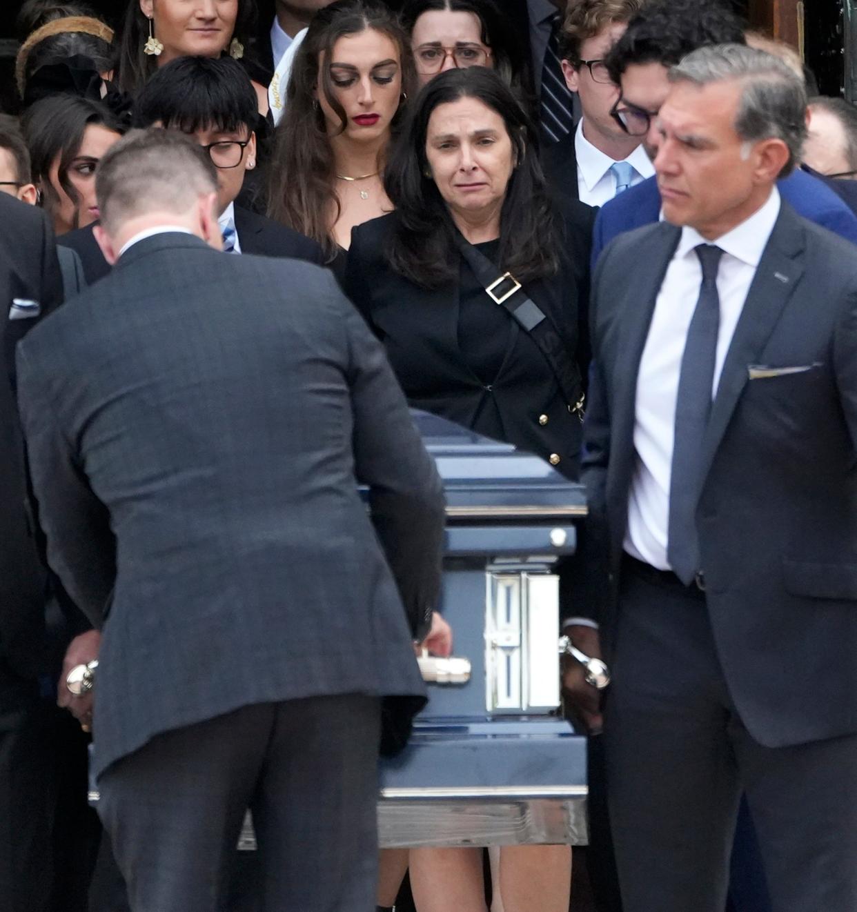 The casket with Marquette University President Michael Lovell is taken from the Church of the Gesu as his wife Amy Lovell looks on after his funeral on West Wisconsin Avenue in Milwaukee on Thursday, June 20, 2024. The service was held for Lovell, 57, who died June 9 in Rome after a three-year battle with cancer.