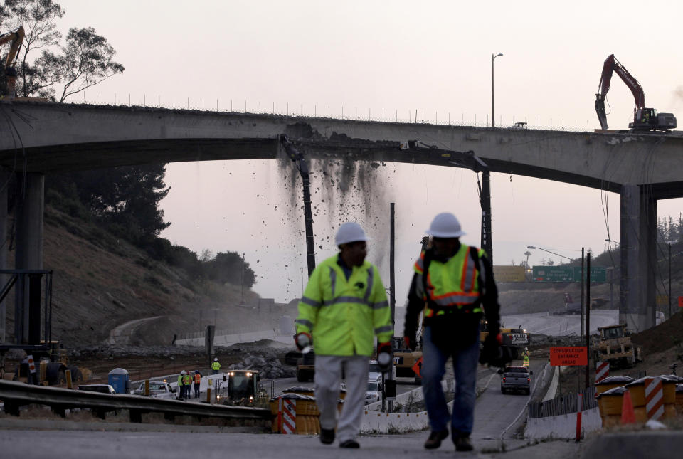 Debris fall from the Mulholland Drive bridge over Interstate 405 as workers take down the bridge in Los Angeles, Saturday, July 16, 2011. A 10-mile stretch of one of the nation's busiest freeways has turned into a virtual ghost road. Ramps to the normally clogged Interstate 405 began shutting down Friday evening before the entire roadway was closed at midnight, setting the stage for a 53-hour construction project that will test whether this car-dependent city can change its driving habits for a weekend. (AP Photo/Jae C. Hong)