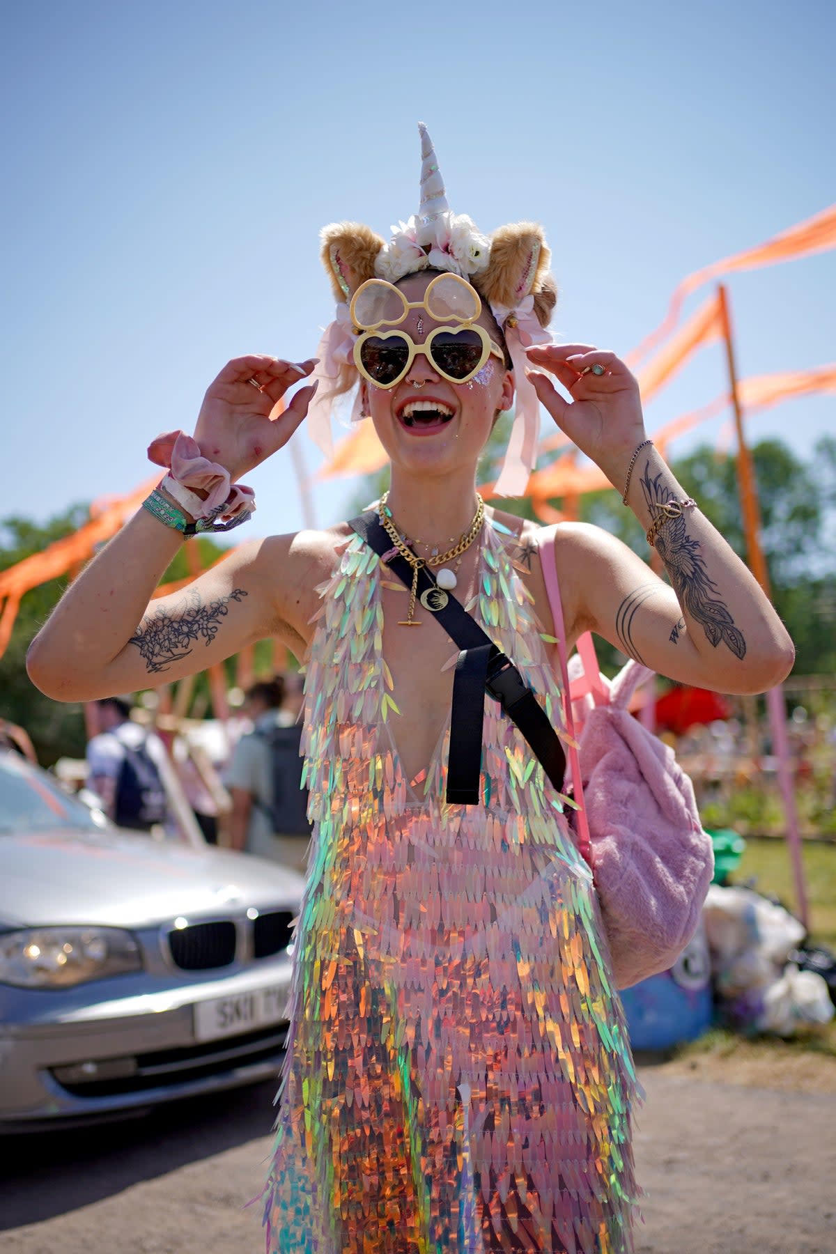 A festivalgoer in a unicorn headband and heart-shaped sunglasses at the Glastonbury Festival (PA)