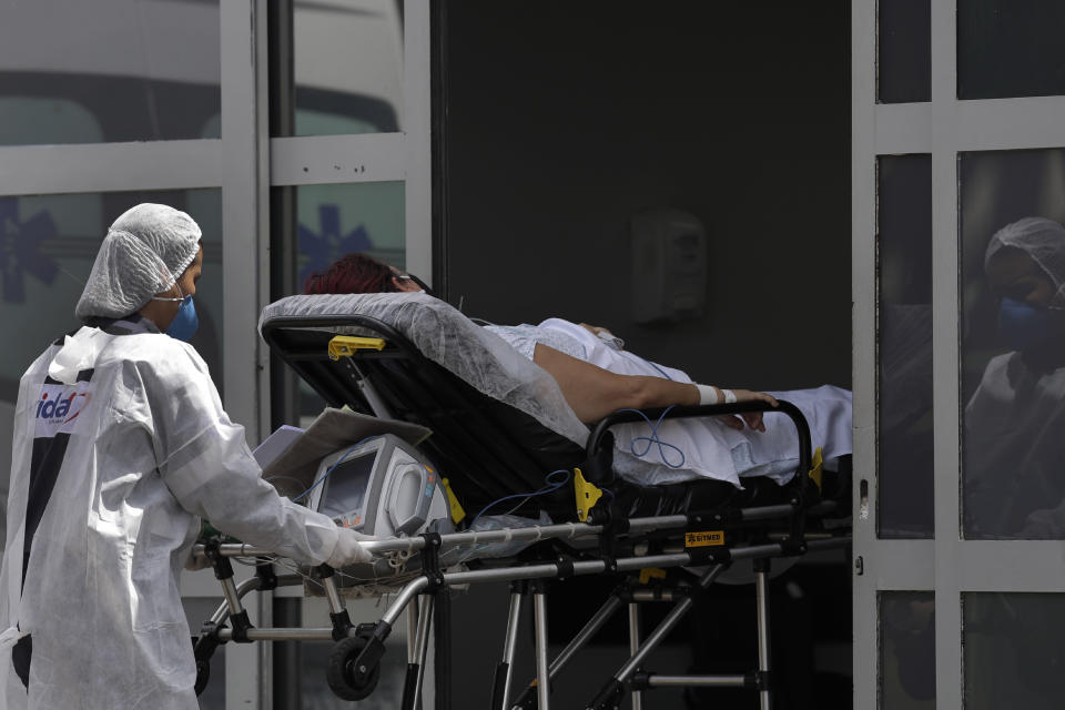 A healthcare worker pushes a patient suspected of having COVID-19 from an ambulance into the HRAN public hospital in Brasilia, Brazil, Wednesday, April 14, 2021. (AP Photo/Eraldo Peres)