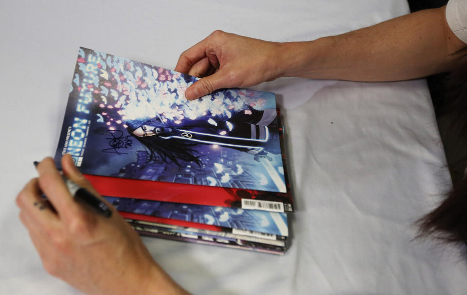 Steve Aoki holds and signs his comic book during a signing of his new "Neon Future" comic book series at Multiverse Corps. Comics on Thursday, May 2, 2019, in Miami. Aoki imagines a future where humans live in harmony with technology. The story is set roughly 30 years from now in a United States that has outlawed advanced technology. A civil war is brewing between people who have integrated technology into their bodies and those who have not. (AP Photo/Brynn Anderson)