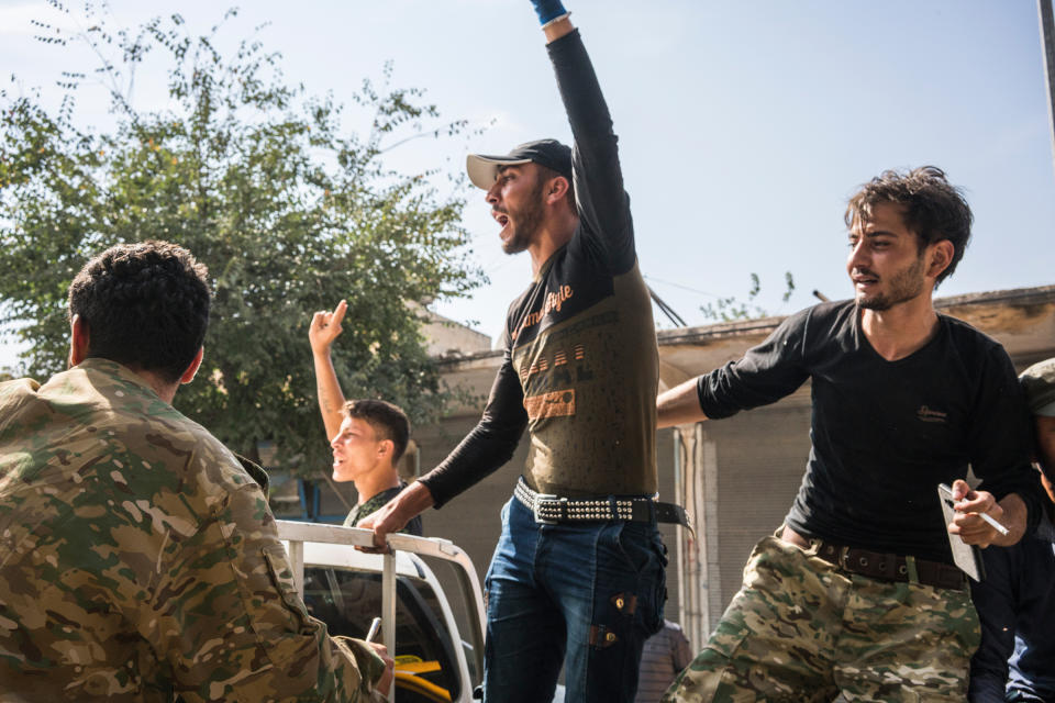 Turkish-backed Syrian rebels shout on the back of a pickup truck on a street in the Turkish border town of Akçakale on Oct. 14, 2019. | Emanuele Satolli