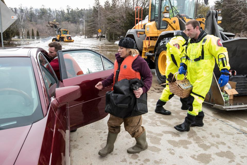 Annette Soukup loads her dog and belongings into her car with help from firefighter Kevin Fabian after being evacuated from her residence due to flooding on the Manitowoc River Thursday, March 21, 2019, in Manitowoc, Wis.