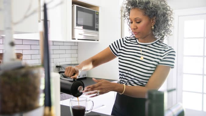 A beautiful black woman with white curly hair makes coffee.