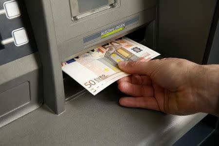 A man receives several 50 euro bank notes from an ATM in this illustration picture taken in Zurich January 16, 2015. REUTERS/Arnd Wiegmann