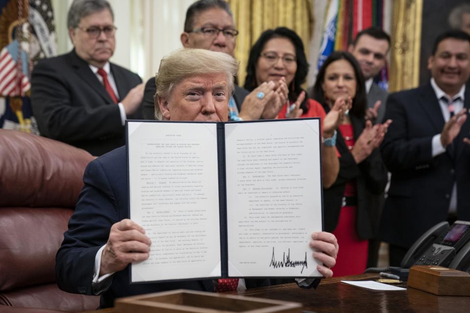 President Donald Trump displays a signed copy of an executive order establishing the Task Force on Missing and Murdered American Indians and Alaska Natives, in the Oval Office of the White House on Nov. 26, 2019, in Washington, D.C.