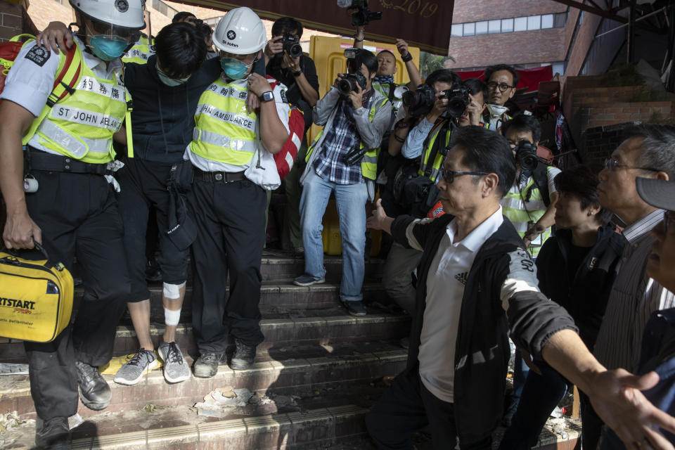 President of the Polytechnic University Jin-Guang Teng, second from right, looks as an injured protester is helped by medics to leave the campus in Hong Kong on Wednesday, Nov. 20, 2019. A small group of protesters refused to leave Hong Kong Polytechnic University, the remnants of hundreds who took over the campus for several days. They won't leave because they would face arrest. Police have set up a cordon around the area to prevent anyone from escaping. (AP Photo/Ng Han Guan)