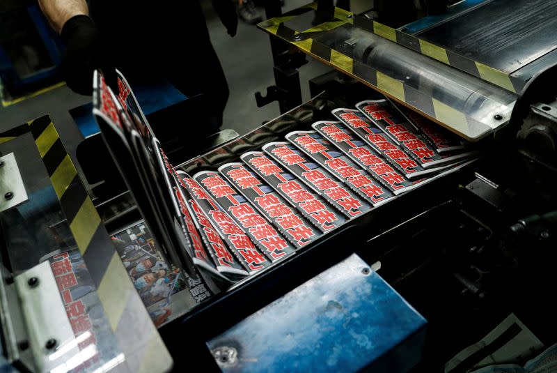 FILE PHOTO: An employee takes a copy of the Apple Daily newspaper, published by Next Media Ltd, with a headline "Apple Daily will fight on" at the company's printing facility in Hong Kong