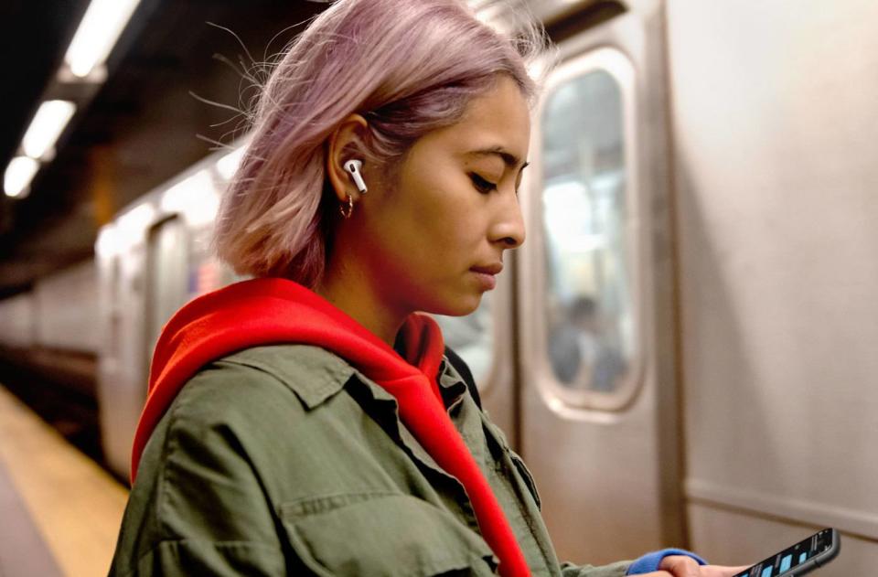 woman wearing a pair of Apple Airpods Pro waiting for a train on platform