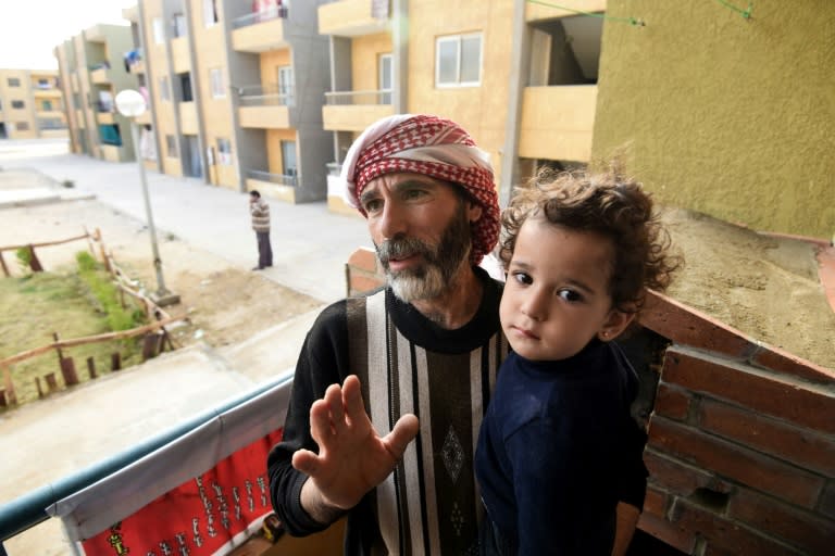 Syrian Mohamed Amin, 43, who fled his country with his family due to the war, stands with his child next to a baking-oven at a make-shift bakery set up on the balcony of his apartment in Cairo