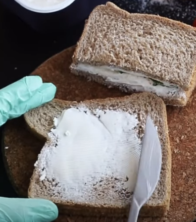 spreading sour cream on a piece of wheat bread