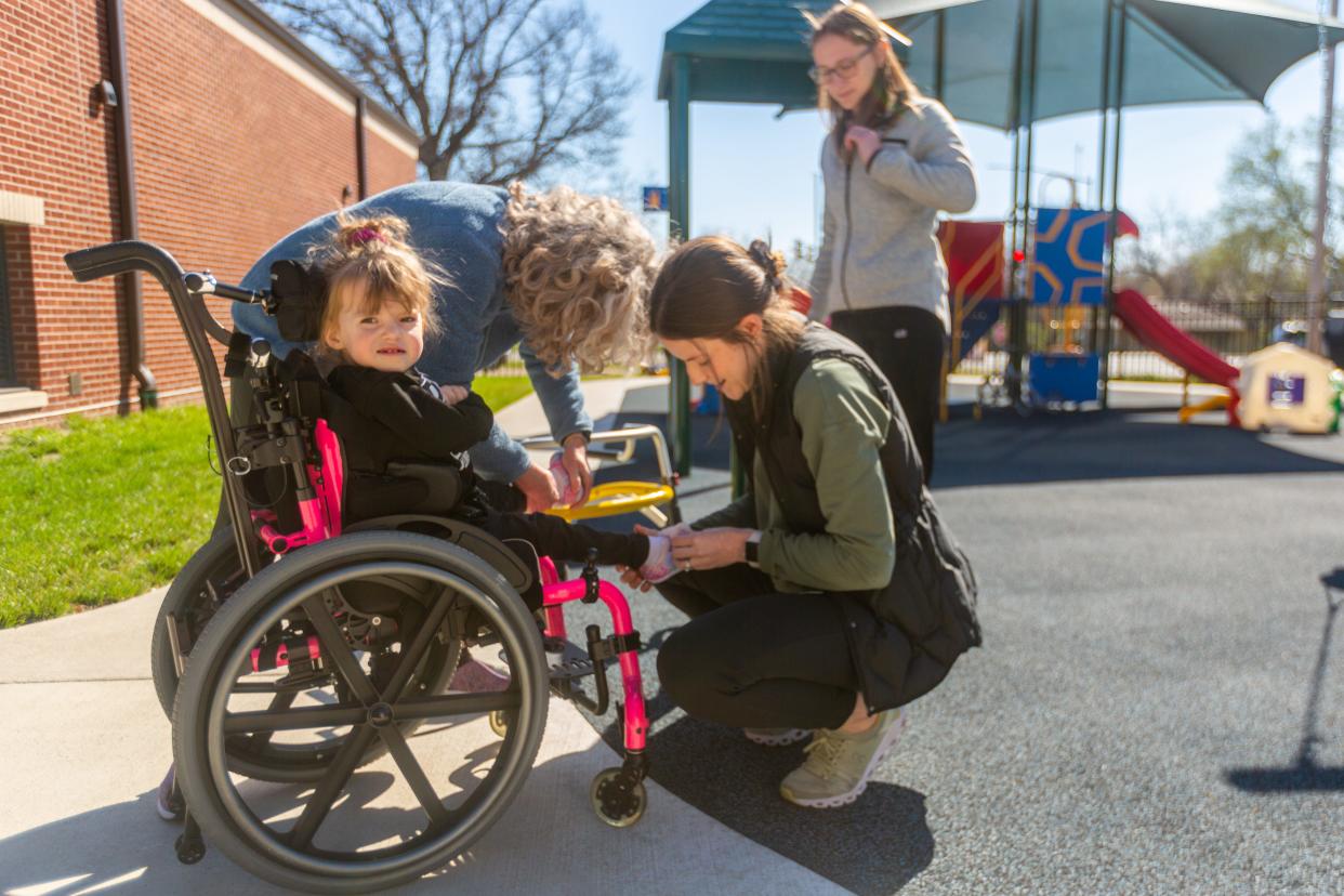 Marie Young, a physical therapist at Topeka USD 501, puts a shoe on the foot of preschooler Amira Payne at the Quinton Heights Education Center.