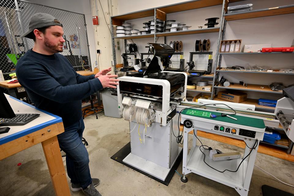WorcLab manager Tyler Ojala in the manufacturing space that includes a Neoden pick-and-place machine and four 3D printers.