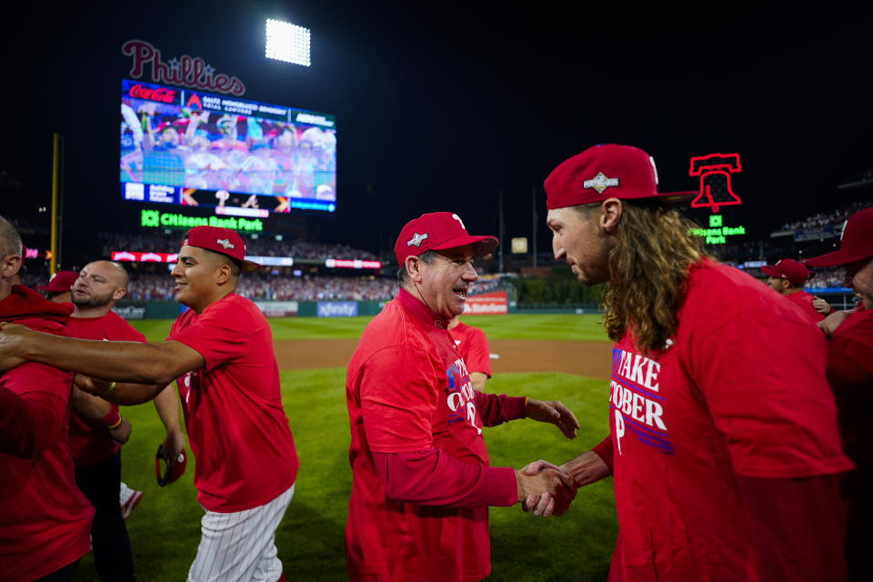 Philadelphia Phillies manager Rob Thomson, center, and pitcher Matt Strahm celebrate the team's win over the Miami Marlins in Game 2 of an NL wild-card baseball playoff series, Wednesday, Oct. 4, 2023, in Philadelphia. The Phillies swept the series, and move on to face the Atlanta Braves. (AP Photo/Matt Slocum)