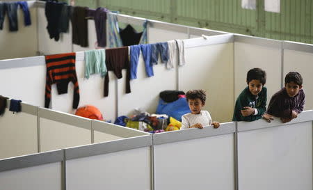 Children watch as they stand on beds in a shelter for migrants inside a hangar of the former Tempelhof airport in Berlin, Germany, December 9, 2015. REUTERS/Fabrizio Bensch