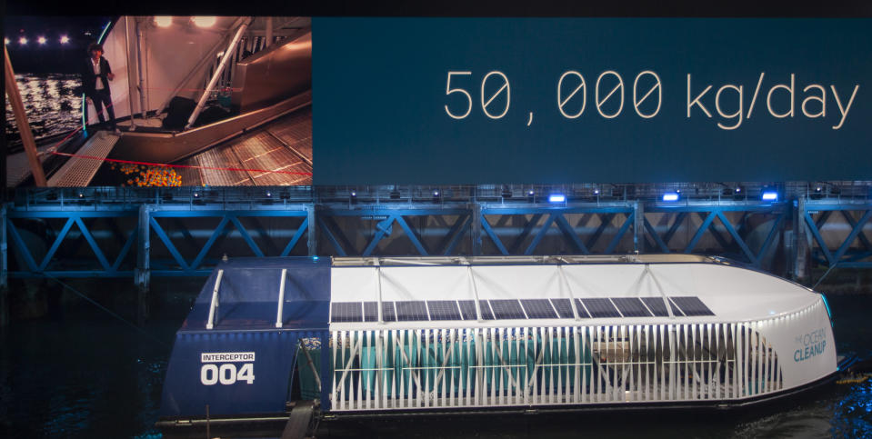 Young Dutch inventor Boyan Slat, on screen left, unveils the Interceptor in Rotterdam, Netherlands, Saturday, Oct. 26, 2019. Slat is taking his effort to clean up floating plastic from the Pacific Ocean to rivers, using the Interceptor, a new floating device to catch garbage before it reaches the seas. The device is able to send a message to a mobile phone when it's full. (AP Photo/Peter Dejong)