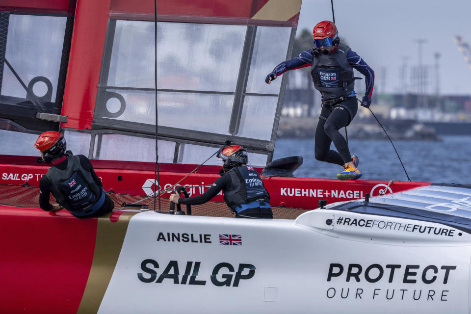 In this photo provided by Sail GP, Ben Ainslie, driver of Team Emirates Great Britain SailGP, runs across the boat as strategist Hannah Mills takes control of the wheel on day one of the Los Angeles Sail Grand Prix at the Port of Los Angeles, Saturday, July 22, 2023. (Felix Diemer/SailGP via AP)