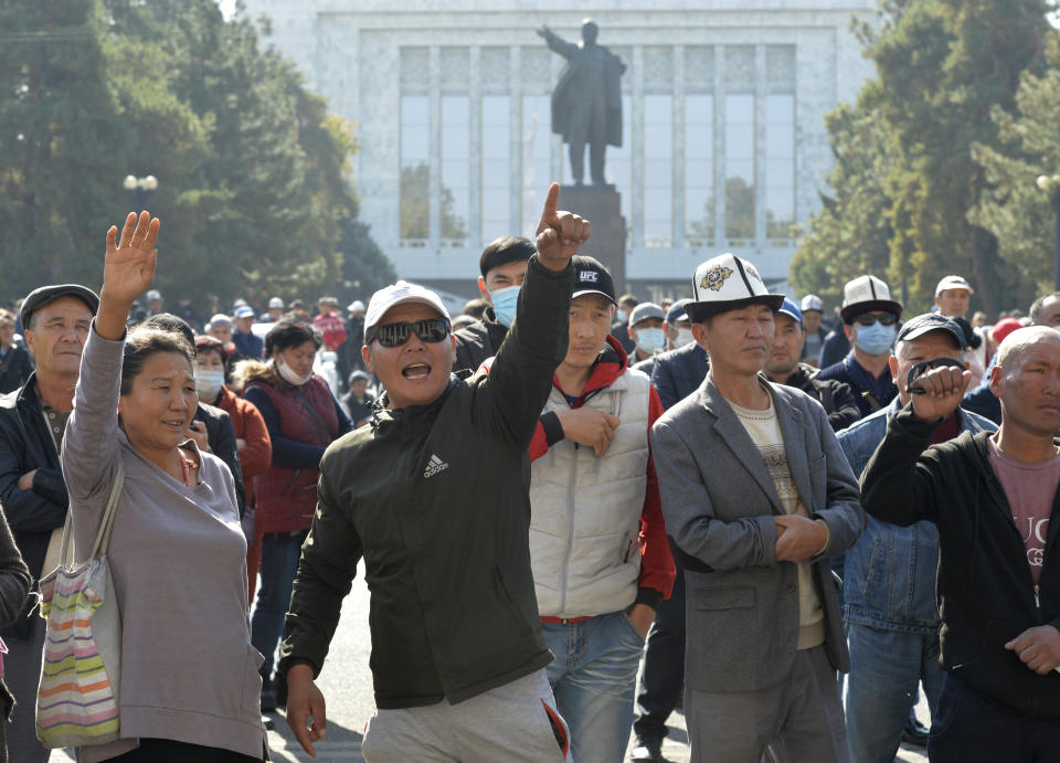 Protesters react listening to a speaker during a rally in front of the government building with a statue of Vladimir Lenin in the background, in Bishkek, Kyrgyzstan, Wednesday, Oct. 14, 2020. Kyrgyzstan's embattled president has discussed his possible resignation with his newly appointed prime minister in a bid to end the political crisis in the Central Asian country after a disputed parliamentary election. President Sooronbai Jeenbekov held talks with Prime Minister Sadyr Zhaparov a day after refusing to appoint him to the post over concerns whether parliament could legitimately nominate him. (AP Photo/Vladimir Voronin)