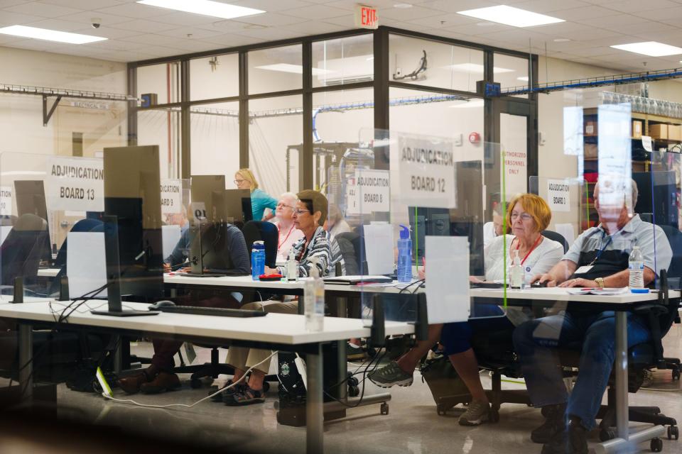 Bipartisan adjudicators work in pairs to count early voter write-in votes and review over-votes at the Maricopa County Tabulation and Election Center on Aug. 1, 2022, in Phoenix, Ariz.